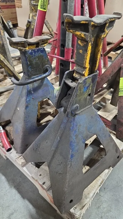Adjustable 5-ton jack stands. Features ratcheting height adjustment, cast support columns with curved saddles, and four-leg bases with locking handles