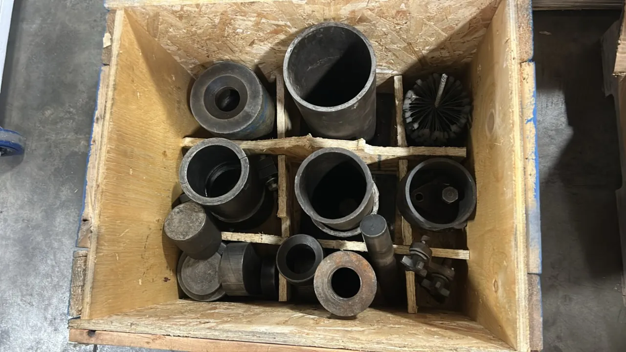 Assorted metal cylinders and tooling accessories with cylinder hone. Includes assorted cylindrical sleeves, collars, pins, and a flexible hone brush.