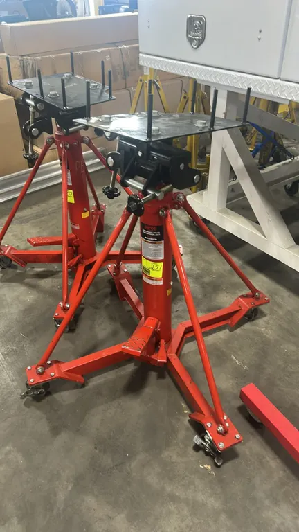 Norco 72700A 1-ton underhoist truck transmission jack. Features foot-operated hydraulic pump and adjustable tilt adapter saddle with positioning pins.