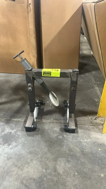 Shop-built metal wheel truing stand. Fabricated from square tubular steel. Features an adjustable screw-action arm with a nylon contact wheel, side gu