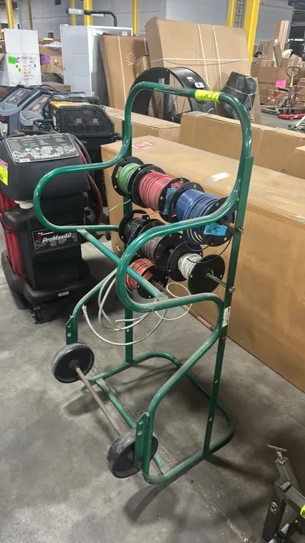 Greenlee 911 portable cable wire reel cart. Features tubular steel frame construction and multi-tier reel spindles. Mounted on two wheels. Includes as