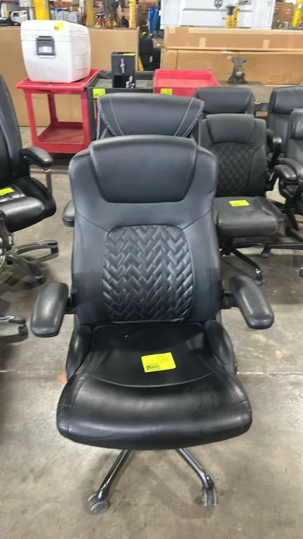 Cushioned executive office chairs. Features black faux leather upholstery with quilted backrest detailing, padded flip-up armrests, and pneumatic heig