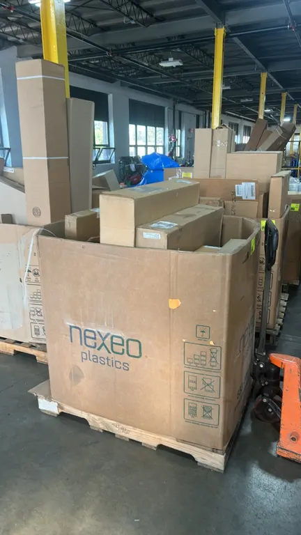 Assorted commercial truck and automotive parts in a Gaylord container. Includes Navistar International radiator assembly (P/N: 2504903C92), Motorcraft
