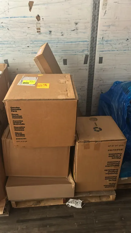 Pallet lot of automotive and diesel engine parts. Includes Ford sliding door trim panel (P/N: DT1Z-61257K14-BJ), Ford inlet manifold assembly (P/N: 9L