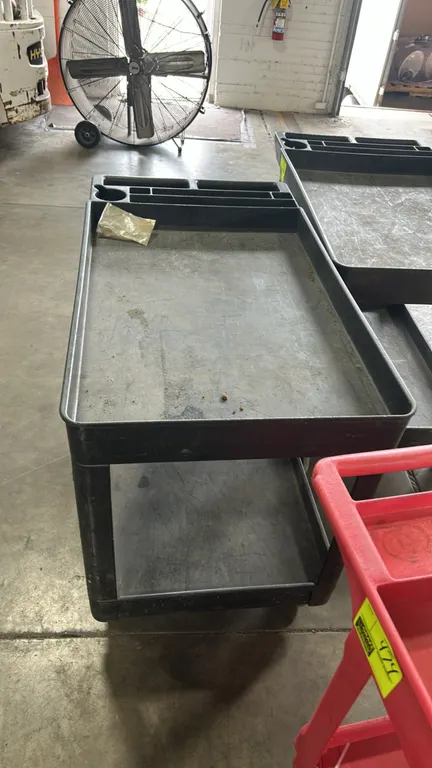 Poly 2-tier utility cart. Features molded plastic construction with deep-lipped shelves and integrated push handle with built-in organizer compartment