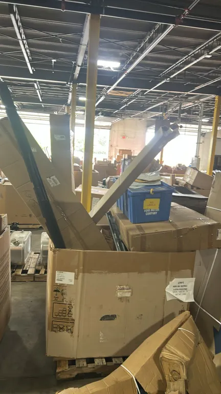 Ford assorted automotive parts lot in Gaylord container. Includes bumper face bar mount (P/N: 8C3Z-17B984-A), Motorcraft A/C condenser assembly (P/N: