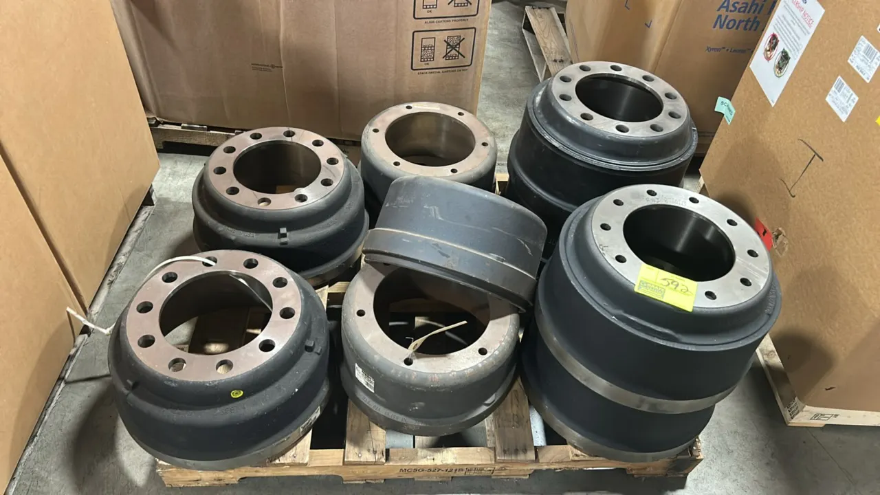Pallet lot of heavy-duty vehicle brake drums. Features assorted commercial vehicle cast iron brake drums in various sizes and bolt configurations.