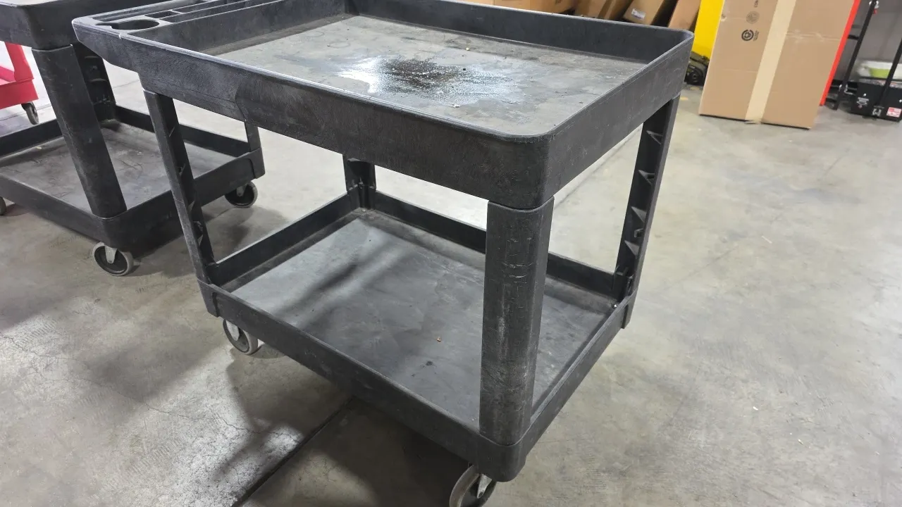Poly 2-tier utility cart. Features molded plastic construction with deep-lip shelves and integrated push handle with storage compartments. 24.5" x 36"