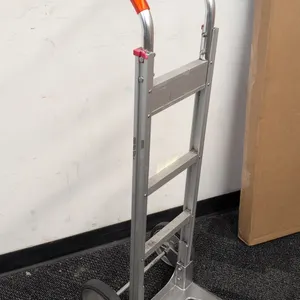 Win-Holt aluminum hand truck. Features a curved loop handle with orange grip, aluminum frame with three cross braces, and open die-cast nose plate. Mo
