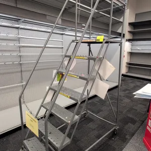 Tri-Arc mobile metal stock ladder. Features 7 steps with perforated slip-resistant treads, top platform, tubular handrails, and upper guardrails. Dime