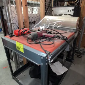 Carriage Trade Service Co. 40" 2-tier metal shrink wrapping station cart. Features top film roll dispenser, manual sealing bar, lower storage shelf, a