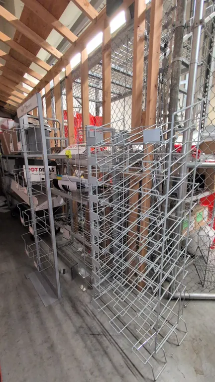 Assorted metal merchandise display racks. Includes (1) multi-tier wire pocket rack with header frame, (1) tiered angled wire display rack, and (1) mul