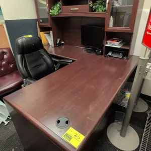 Laminate wood L-shaped desk with hutch. Features cherry-tone finish, upper hutch cabinets with framed glass doors, center storage cubbies, under-desk 