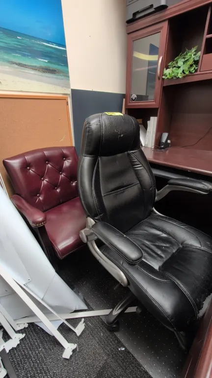 Assorted faux leather chairs. Includes (1) black high-back executive swivel chair on a 5-star caster base and (1) burgundy button-tufted guest armchai