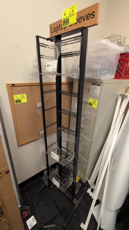Metal 3-sided merchandise display rack. Features black metal frame, clear acrylic display pockets, and a top header sign. 20" x 65"H.
