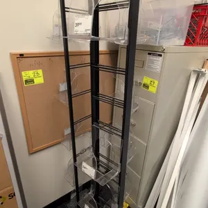 Metal 3-sided merchandise display rack. Features black metal frame, clear acrylic display pockets, and a top header sign. 20" x 65"H.