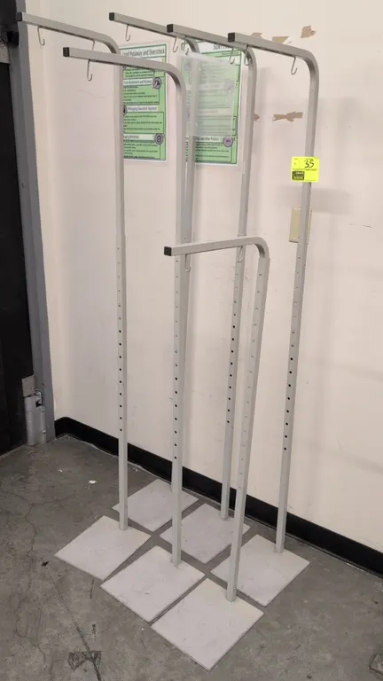 Metal adjustable hanging sign stands. Features telescoping uprights with push-button height adjustment, top arms with dual hanging hooks, and square f