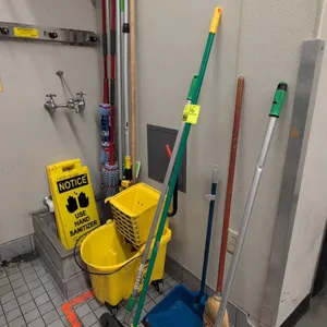 Assorted cleaning supplies package. Includes yellow mop bucket with wringer on casters, folding notice/caution floor signs, upright dustpan, corn broo