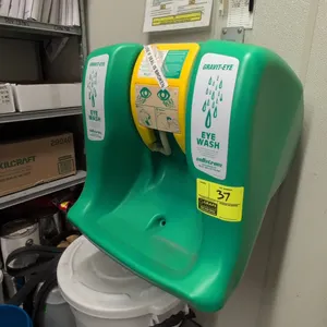 Sellstrom Gravit-Eye emergency eyewash station. Features green polyethylene construction, fold-down yellow activation tray with dual spray heads, top 