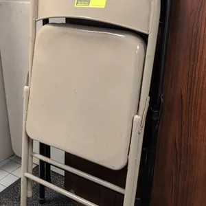 Assorted metal folding chairs. Includes (1) beige painted steel folding chair and (1) black folding chair with padded vinyl seat and backrest. Feature