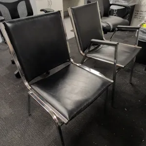 Faux leather guest chairs. Features black faux leather upholstered cushioned seats and backrests on chrome-finished metal frames. Includes both arm an