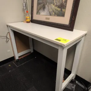 Laminate portable table. Features a white laminate top and metal frame. 42"L. Mounted on casters. Tabletop items not included.