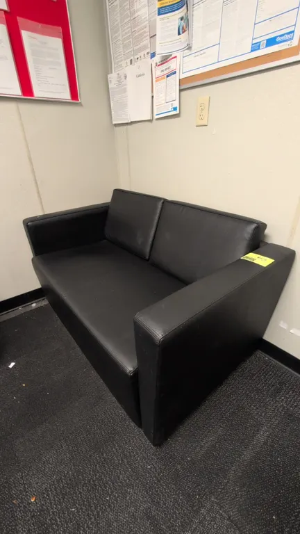 Faux leather cushioned sofa. Features black faux leather upholstery, two-cushion backrest, and track arms. 55"L.