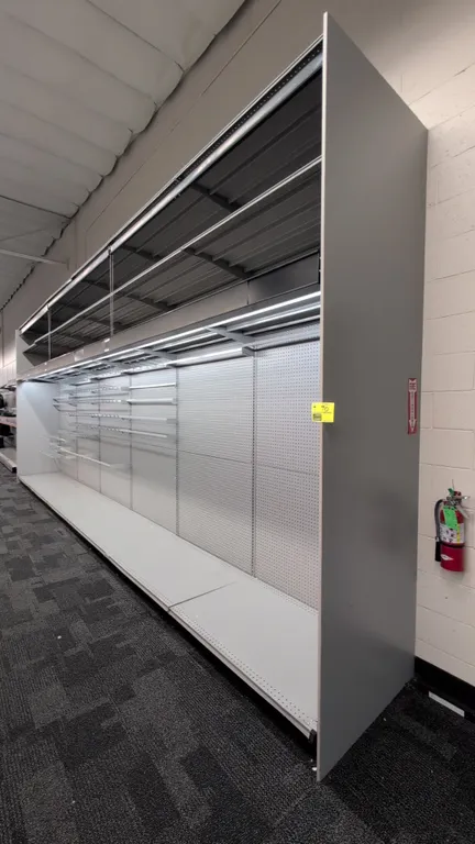 24'L of Madix wall shelving. 120"H uprights with 30"D base shelves. Features gray finish, pegboard backing, integrated canopy lighting, overhead shelv