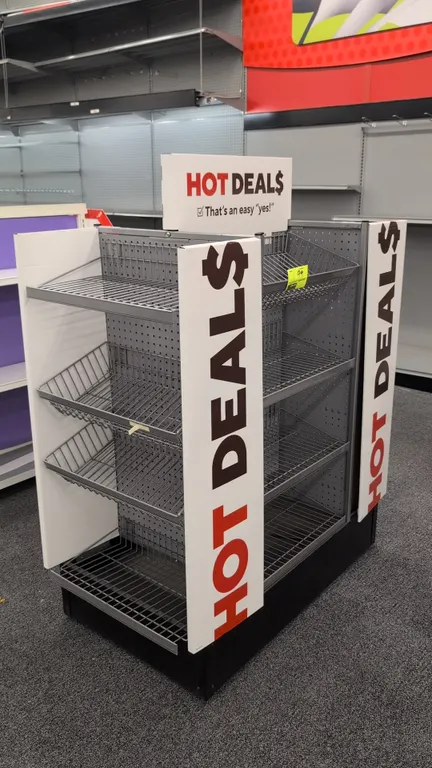 Portable 4-sided metal merchandise display rack. Features wire basket shelving, perforated metal pegboard backing, and 'Hot Deals' promotional signage