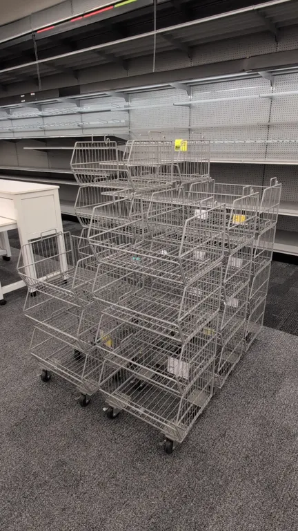 Metal portable merchandise racks. Features multi-tier stackable wire baskets with open-front bin design. 18" wide. Mounted on swivel caster bases.