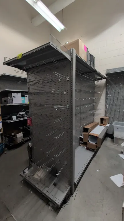 19'L of Madix gondola shelving. 78"H uprights with 18"D base shelves. Features gray finish, pegboard backing, and top shelf with wire retainers. Conte