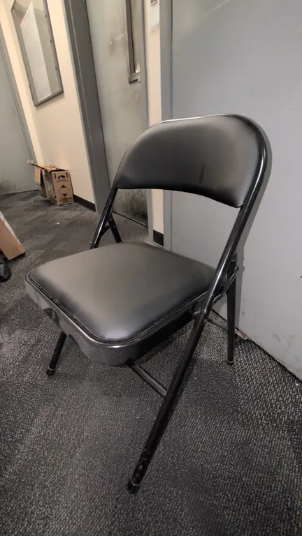 Faux leather cushioned folding chairs. Features black faux leather padded seats and backrests mounted on black metal folding frames.