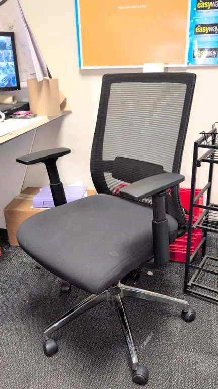 2020 Marrett UN53249 mesh task office chair. Features a black mesh back, upholstered fabric cushioned seat, adjustable armrests, and lumbar support. M