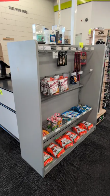 Laminate merchandise display rack. Features gray laminate end panels, horizontal hanging rails with display hooks, and lower wire shelves. 50" x 18" x