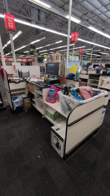 Laminate retail checkout lane counter. Features under-counter storage shelving and cabinet space, black countertops with protective bumper trim, and a