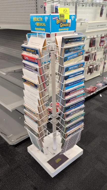 Metal rotating merchandise display rack. Features a 4-sided wire pocket carousel and top signage header. 18" x 60"H. Mounted on a square base. Content