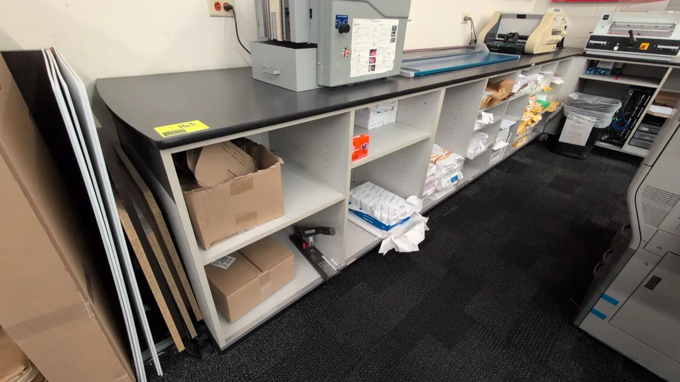 L-shaped laminate countertop with base cabinets. Features black laminate work surface, multiple pull-out storage drawers, and open adjustable shelving