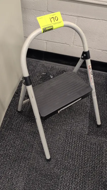 Cosco folding 1-step stool. Features a tubular metal frame, molded textured poly step tread with push-and-fold release mechanism, top carry handle arc
