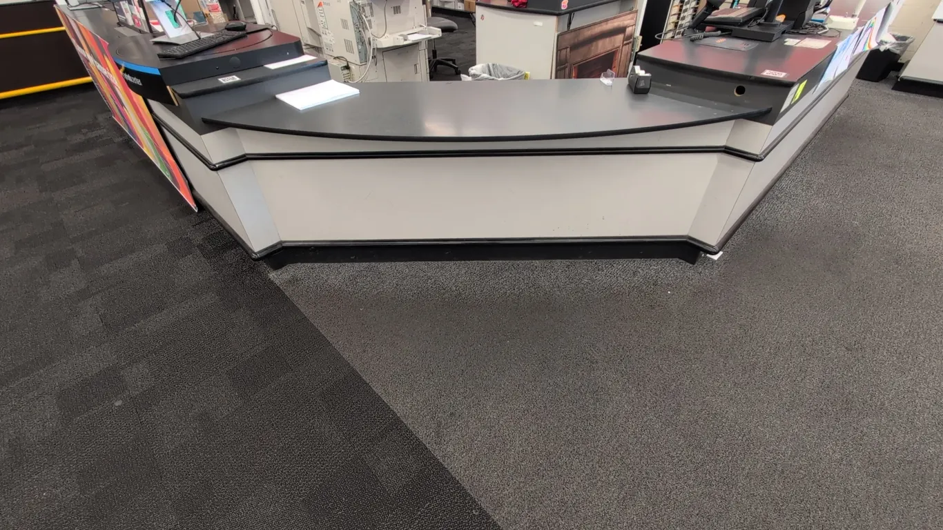Laminate U-shaped service counter. Features under-counter storage shelving, black laminate countertop, and pole-mounted illuminated checkout light. Me