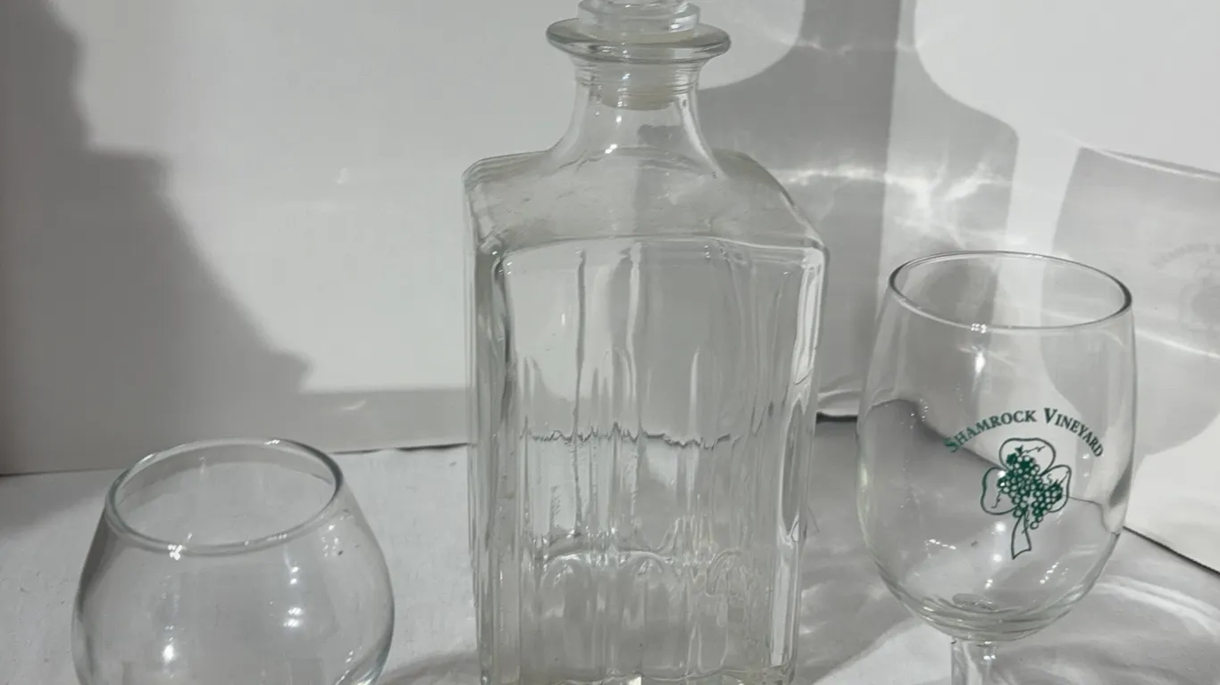 Lot of three vintage items. A whiskey decanter a Jim Beam glass and a shamrock vineyard wine glass.