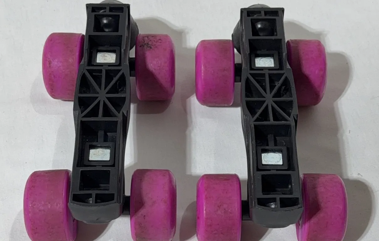 Pair of attachable strap-on heel roller skate frames with black plastic bases and pink wheels