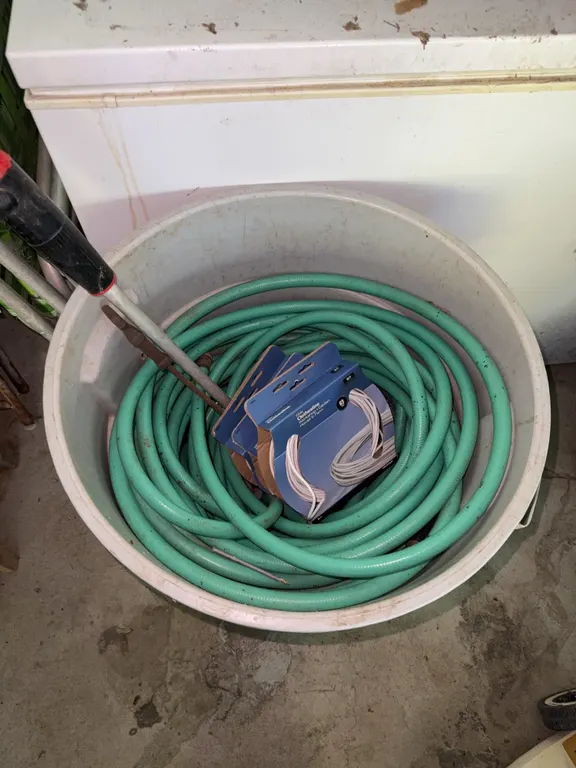 Trash full of garden hoses and clothes line