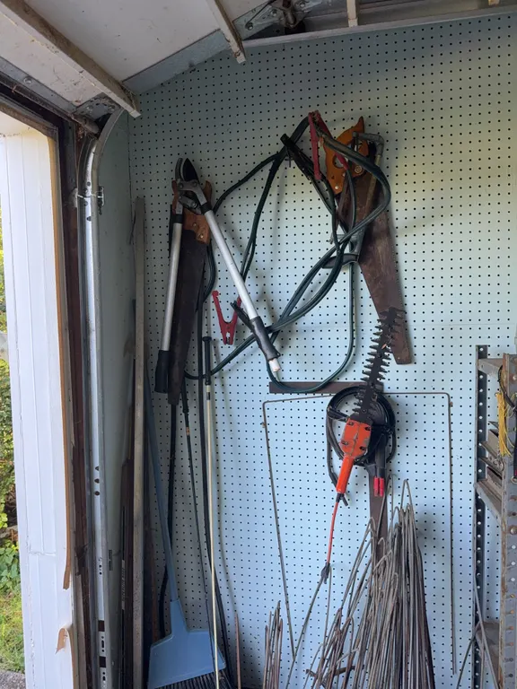 Various tools on the wall and metal in buckets along with a old heater