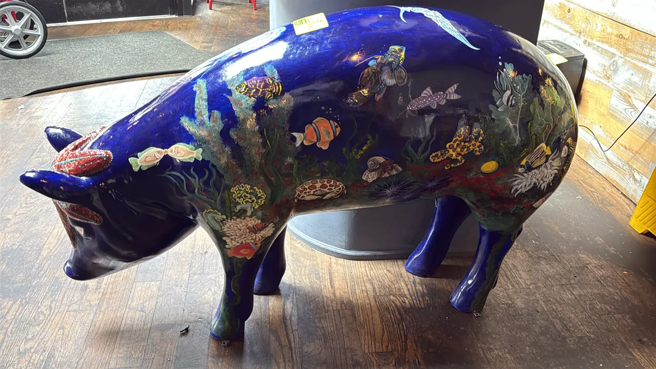 A Painted Pig Display Statue. A life-size decorative pig statue painted in a detailed marine and ocean reef motif over a deep blue ground, featuring t
