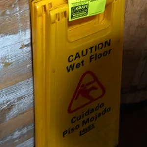Lavex folding wet floor signs. Features yellow plastic construction with bilingual English and Spanish 'Caution Wet Floor / Cuidado Piso Mojado' text 