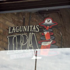 Lagunitas lighted beer sign. Features 'Lagunitas IPA Chicago' lettering with a UFO tractor-beam graphic and beer glasses motif. Equipped with metal fr