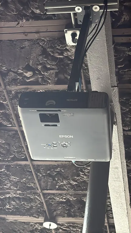 Epson projector with 9' projector screen. Features HDMI, VGA, LAN, USB, and composite video inputs. Screen measures 9'L. Includes ceiling mounting bra