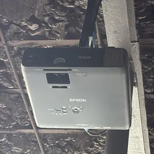 Epson projector with 9' projector screen. Features HDMI, VGA, LAN, USB, and composite video inputs. Screen measures 9'L. Includes ceiling mounting bra