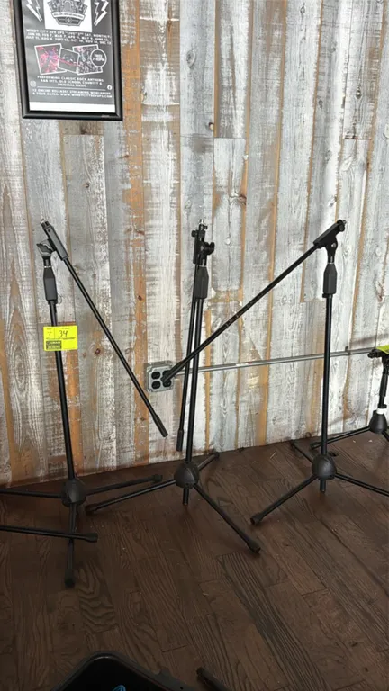 Tripod boom microphone stands. Features adjustable height clutches, adjustable boom arms, and threaded mic mounts. Finished in black. Mounted on foldi