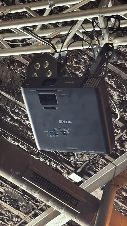 Epson projector with 9' projector screen. Features HDMI, VGA, LAN, and composite video inputs with integrated top controls. Paired with a 9' projector
